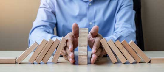 businessman hand stopping falling wooden blocks dominoes 42256 1113 1 min